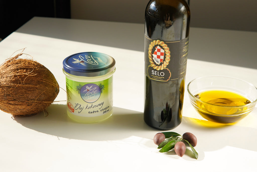 Bottle of Selo Croatian Olive Oil next to a jar of coconut oil on a kitchen countertop, symbolizing the comparison between the two oils.