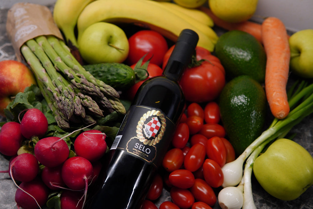 Selo olive oil bottle showcased with vibrant vegetables in the background.